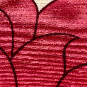 May include: Close-up of a red fabric with a textured weave. The fabric has a black floral pattern.