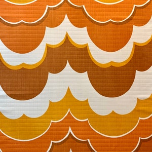 Op de afbeelding: Een herhalend patroon van gestileerde wolkvormen in tinten bruin, oranje en geel met witte contouren. Het ontwerp heeft een retro-esthetiek, die doet denken aan vintage behang of stof.