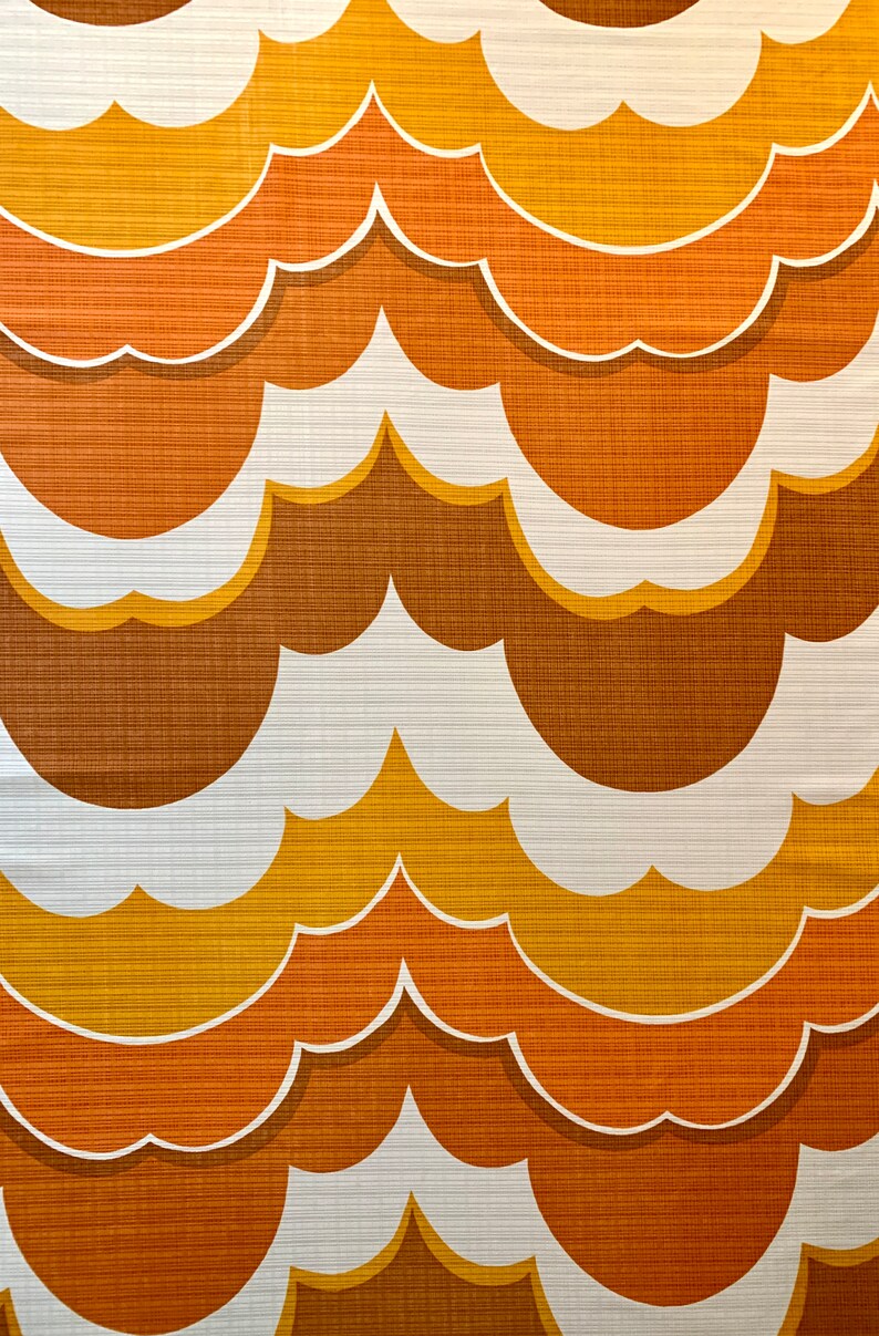 Op de afbeelding: Een herhalend patroon van gestileerde wolkvormen in tinten bruin, oranje en geel met witte contouren. Het ontwerp heeft een retro-esthetiek, die doet denken aan vintage behang of stof.
