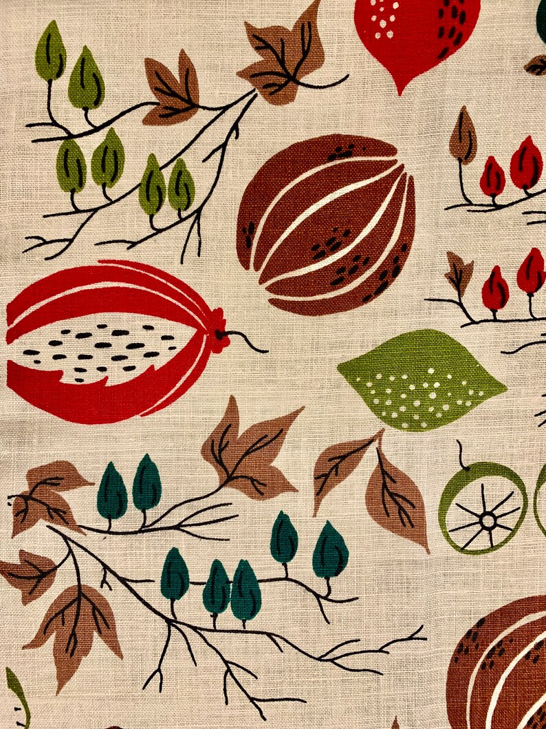 May include: A beige fabric with a repeating pattern of brown, red, and green stylized fruits and leaves. The pattern is abstract and reminiscent of a vintage textile design.
