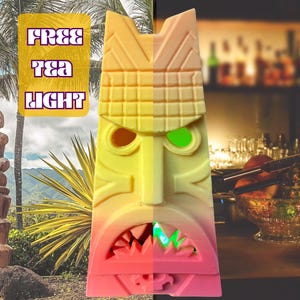 May include: A vibrant tiki mask in shades of yellow, orange, and pink, featuring a stern expression and glowing green eyes. The mask has sharp teeth. The text "FREE TEA LIGHT" is displayed in a yellow banner. The background shows a tropical setting.