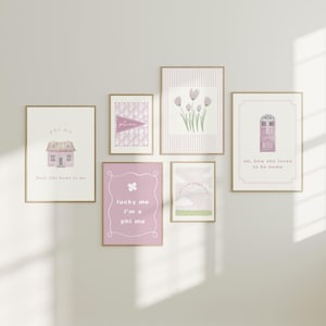 Könnte beinhalten: Sechs gerahmte Kunstdrucke in Rosa- und Weißtönen. Die Drucke zeigen ein Haus, Blumen, eine Tür und Text mit der Aufschrift "phi mu" und "feels like home to me". Die Rahmen sind hellbraun. Die Drucke hängen an einer weißen Wand.