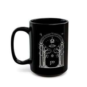 May include: Black ceramic mug with a white design of an archway with a tree on each side, a star, and the words "Not all those who wander are lost."