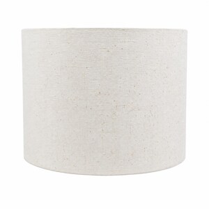 May include: A cylindrical drum lampshade featuring a textured, off-white fabric surface with subtle, natural-looking flecks of tan and brown throughout the material, creating a neutral appearance with a consistent, woven-like finish across the exterior.