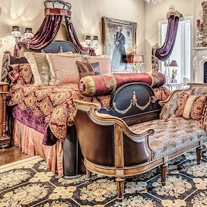 May include: A luxurious bedroom with a large bed featuring a burgundy canopy, a patterned comforter, and a variety of pillows. A small, tufted bench with a faux fur seat sits at the foot of the bed.