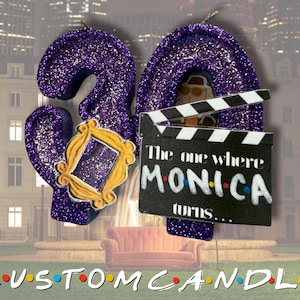 May include: A purple glitter candle in the shape of the number 30, with a gold frame and a film clapperboard that reads "The one where Monica turns..." The word "CUSTOM CANDLE" is at the bottom.