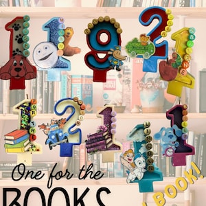 May include: A selection of number-shaped custom candles, each featuring cartoon characters and decorative details. The candles are presented on a bookshelf, with the text "CUSTOM CANDLES!" and "One for the BOOKS ANY BOOK!"