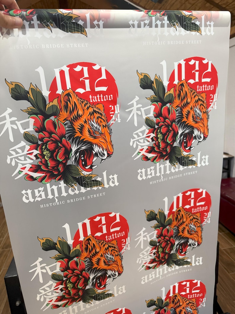 May include: A repeating pattern of a red circle with the number 1032 and the word "tattoo" inside. The circle is surrounded by a tiger with a red flower and the Japanese characters "和" and "愛" in black. The text "ashtala" and "HISTORIC BRIDGE STREET" are also included in the design.