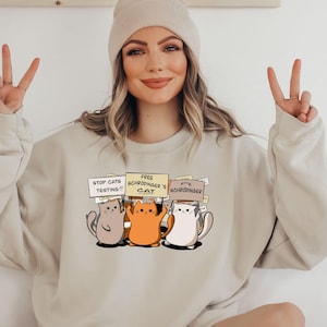 May include: A white ceramic mug with a black handle and the text "But First, Coffee" in a bold, black font. The mug is set against a blurred background, suggesting a cozy setting. The mug appears to be approximately 4 inches tall.