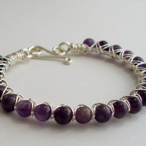 May include: A silver wire wrapped bracelet with purple amethyst beads.