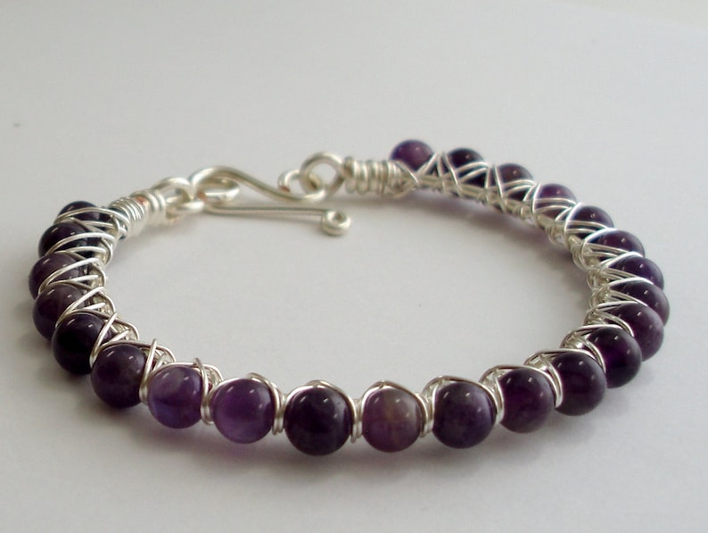 May include: A silver wire wrapped bracelet with purple amethyst beads.