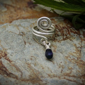 May include: Silver wire ear cuff with a spiral design and a dangling dark blue gemstone.
