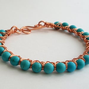May include: A copper wire wrapped bracelet with turquoise blue beads.