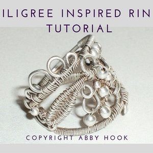 Op de afbeelding: Een zilveren filigraanring met een delicaat ontwerp en kleine kralen. De ring is handgemaakt en heeft een uniek, ingewikkeld patroon. De afbeelding bevat de tekst "FILIGREE INSPIRED RING TUTORIAL" en "COPYRIGHT ABBY HOOK".
