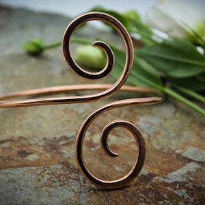 May include: A copper wire bracelet with a double spiral design. The bracelet is open and adjustable.