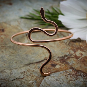 May include: A rose gold snake-shaped wire bracelet. The bracelet is open and adjustable to fit most wrists.