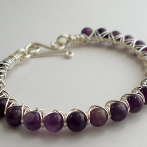 May include: A silver wire wrapped bracelet with purple amethyst beads.