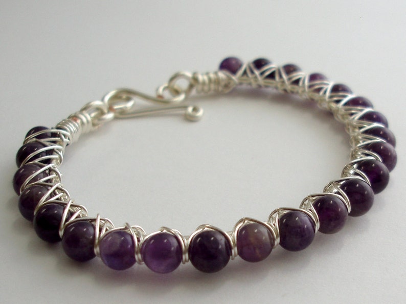 May include: A silver wire wrapped bracelet with purple amethyst beads.