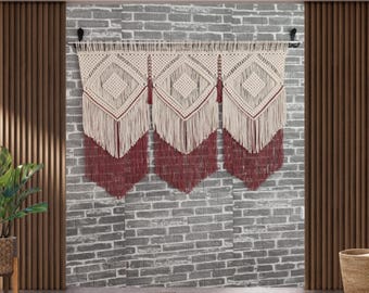 May include: A white and red macrame wall hanging with a geometric pattern. The hanging is made of cotton cord and has a fringe border.