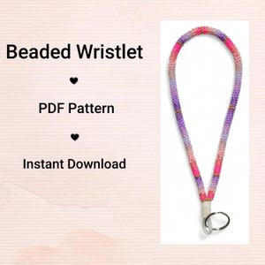 Puede incluir: Un brazalete de cuentas en tonos rosa, morado y dorado. El brazalete está hecho de pequeñas cuentas y tiene un lazo para la muñeca y un anillo de metal. El texto a la izquierda dice "Beaded Wristlet", "PDF Pattern" e "Instant Download".