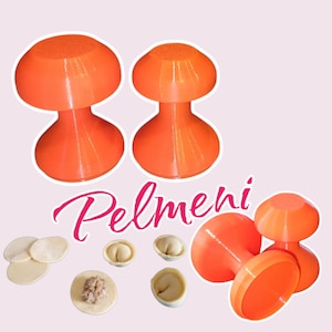 Könnte beinhalten: Drei orangefarbene Plastikwerkzeuge zum Herstellen von Pelmeni, einer Art russischer Knödel. Die Werkzeuge sind pilzförmig mit einer flachen Basis. Das Wort "Pelmeni" ist in rosa Buchstaben unter den Werkzeugen geschrieben.