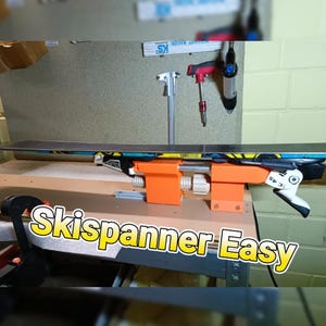 Puede incluir: Un dispositivo de ajuste de esquí naranja con un esquí sujeto en su lugar. El dispositivo está etiquetado como "Skispanner Easy".