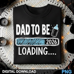Peut inclure: T-shirt noir à col rond avec l'inscription blanche "DAD TO BE". En dessous, une barre de chargement bleue avec "2026" et le mot "LOADING...." est affichée. Un dessin de biberon est également présent.