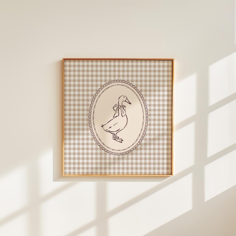 This vintage-inspired digital art print features a hand drawn duck with bow illustration and a neutral beige brown gingham background. This square print make the perfect gift for wall decor for a vintage cottage and elegant nursery room for a baby girl or boy, bedroom or even the kids game room.