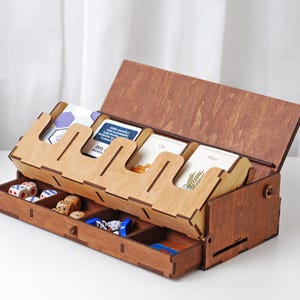 以下が含まれることがあります： 蓋を開けるとカードを収納できる5つの仕切りが現れる木製の箱。箱には、サイコロやその他の小さなゲームピースを収納できる引き出しも付いています。