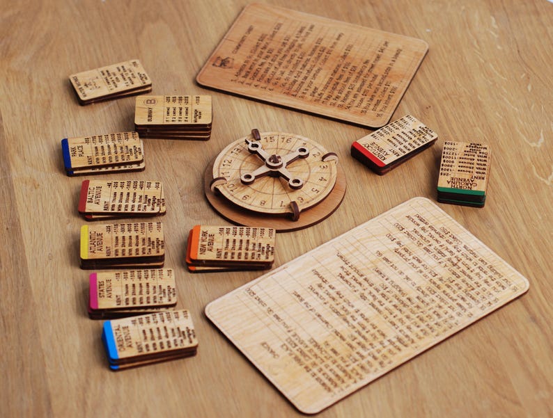 May include: A wooden board game with a spinning wheel, cards, and a score sheet. The cards are labeled with different locations, such as "Baltic Avenue" and "Park Place". The score sheet has a grid with numbers and spaces for recording scores.