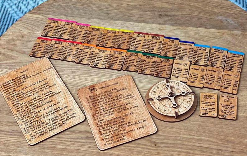 May include: A wooden Monopoly game set with property cards, chance cards, community chest cards, a spinner, and utility cards. The cards are color-coded and feature different properties, such as Boardwalk and Park Place.