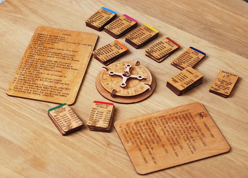 May include: A wooden board game with a wooden spinner and cards. The cards are labeled with different locations, such as "Boardwalk" and "Kentucky Avenue". The game also includes a wooden wheel with a pointer.