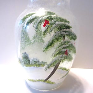 May include: A white ceramic mug with a black handle and the text "But First, Coffee" in a black, bold font. The mug is on a white surface.