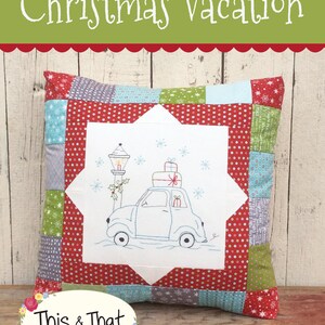 May include: A white cushion with a red, green and blue patchwork design. The centre of the cushion features an embroidered design of a car with presents on top, driving past a street lamp. The text "Christmas Vacation" is at the top of the image and "This & That" is at the bottom of the image. The text "#313" is in the bottom right corner of the image.