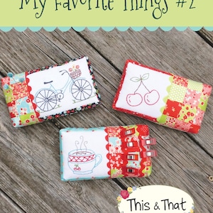 May include: Three small quilted pincushions with embroidered designs. The first pincushion features a bicycle with a basket of flowers, the second pincushion features two cherries, and the third pincushion features a cup of coffee with steam rising from it. The pincushions are on a wooden surface. The text "My Favorite Things #2" is at the top of the image. The text "This & That" is at the bottom of the image.