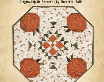 Puede incluir: Un patrón de acolchado titulado "This & That" de Sherri K. Falls. El patrón se llama "Mini Pumpkin Patch" y está numerado #185. El patrón de acolchado presenta un diseño de patchwork con calabazas y hojas.