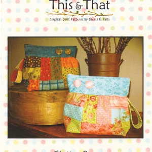 May include: Two colorful patchwork fabric bags with a ruffled top and a handle. The bags are made from scraps of fabric in various patterns and colors, including red, blue, green, yellow, and pink. The bags are labeled "Clutter Bug" and "#088".