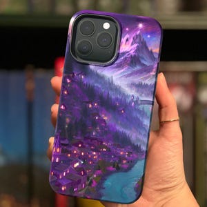 May include: Purple phone case with a fantasy landscape design featuring a village, mountains, and a starry sky.
