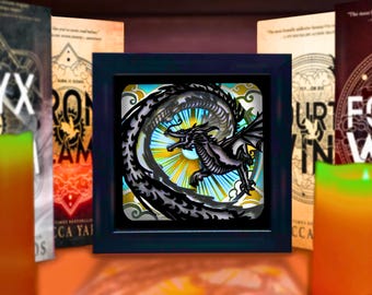 May include: A square black frame containing a layered paper art piece featuring a dark dragon in flight against a bright yellow and blue sunburst background with stylized clouds, flanked by four books with visible text and graphic designs.