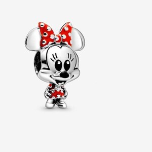 May include: A silver charm featuring Minnie Mouse. The charm has a red bow with white polka dots, a red dress with white polka dots, and black eyes. The charm is a three-dimensional design.