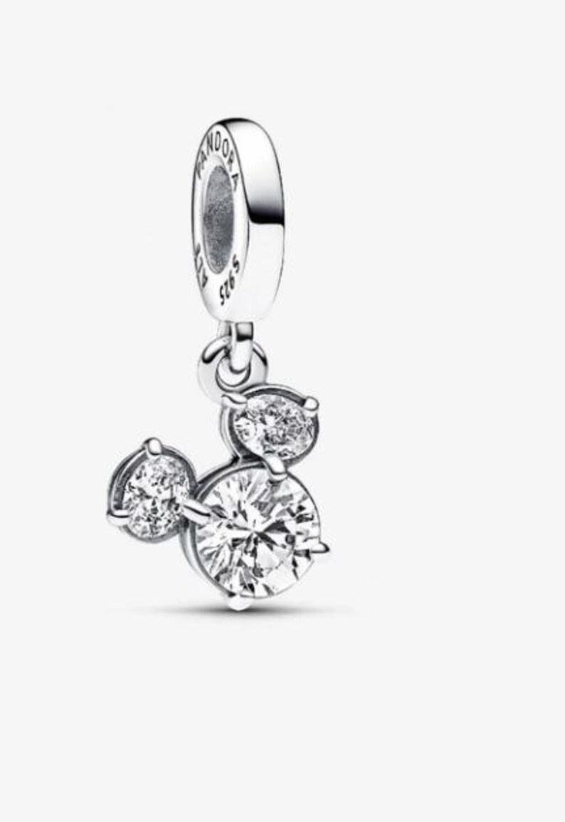 May include: A silver charm with three clear, round cubic zirconia stones arranged in a Mickey Mouse head shape. The charm has a loop at the top with the brand name "Pandora" and "S925 ALE" engraved on it.