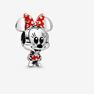 May include: A silver charm featuring Minnie Mouse. The charm has a red bow with white polka dots, a red dress with white polka dots, and black eyes. The charm is a three-dimensional design.
