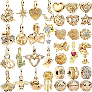 May include: A selection of gold-coloured charm pendants, including hearts, stars, flowers, and other decorative shapes. Some charms feature gemstones or intricate designs, suitable for bracelets or necklaces.