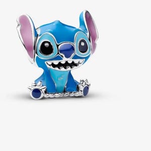 May include: A blue and silver charm featuring the character Stitch from the Disney movie Lilo & Stitch. The charm has large black eyes, a wide grin, and large ears with pink inner details. The charm is made of metal and enamel.