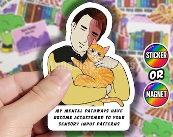 Op de afbeelding: Een sticker of magneet met een cartoonillustratie van een man die een oranje tabbykat vasthoudt. De tekst luidt: "MIJN MENTALE PADEN ZIJN GEWEND AAN UW ZINTUIGLIJKE INPUTPATRONEN." De sticker heeft een regenboogrand en de woorden "STICKER" en "MAGNEET".