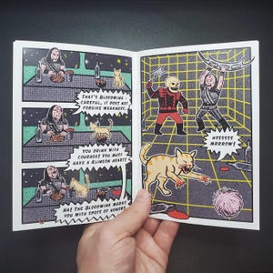 Op de afbeelding: Een stripboekpagina met illustraties van Klingons, katten en tekstballonnen. De illustraties zijn in retrostijl met een rasterachtergrond. De tekst bevat zinnen als "That's Bloodwine" en "Hssssss Mrrrow!"