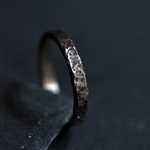 May include: A silver hammered band ring with a textured finish.