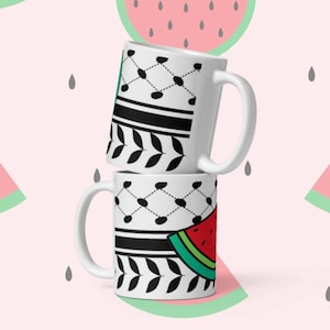 Pode incluir: Duas canecas de cerâmica branca com padrões geométricos em preto e branco e um design de melancia. As canecas estão empilhadas uma em cima da outra. O fundo é um padrão rosa de melancias.
