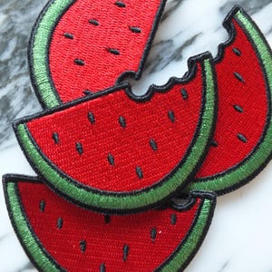 May include: Embroidered watermelon slice patches. The patches feature a red centre, green rind, and black seeds. One patch has a bite taken out of it. Ideal for adding a fruity touch to clothing or accessories.