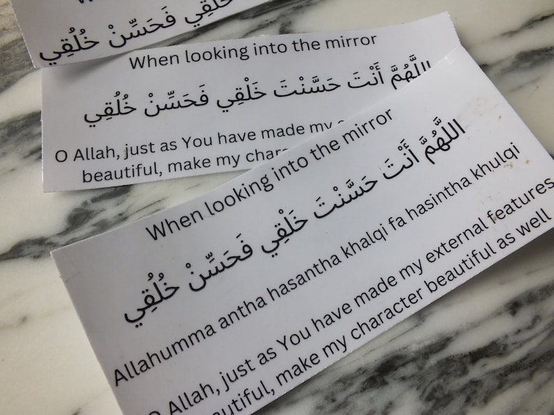 May include: Two white cards with Arabic text and English text that reads "When looking into the mirror, O Allah, just as You have made my external features beautiful, make my character beautiful as well." The text is repeated on both cards.